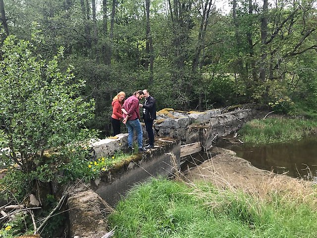 Foto på tre personer som inspekterar dammen